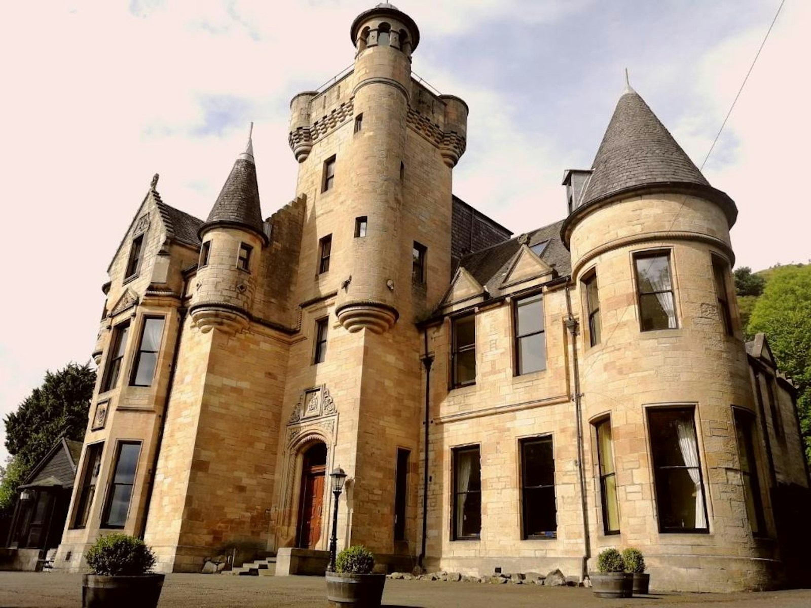 Daytime exterior of Broomhall Castle Hotel showing its stone towers and entrance