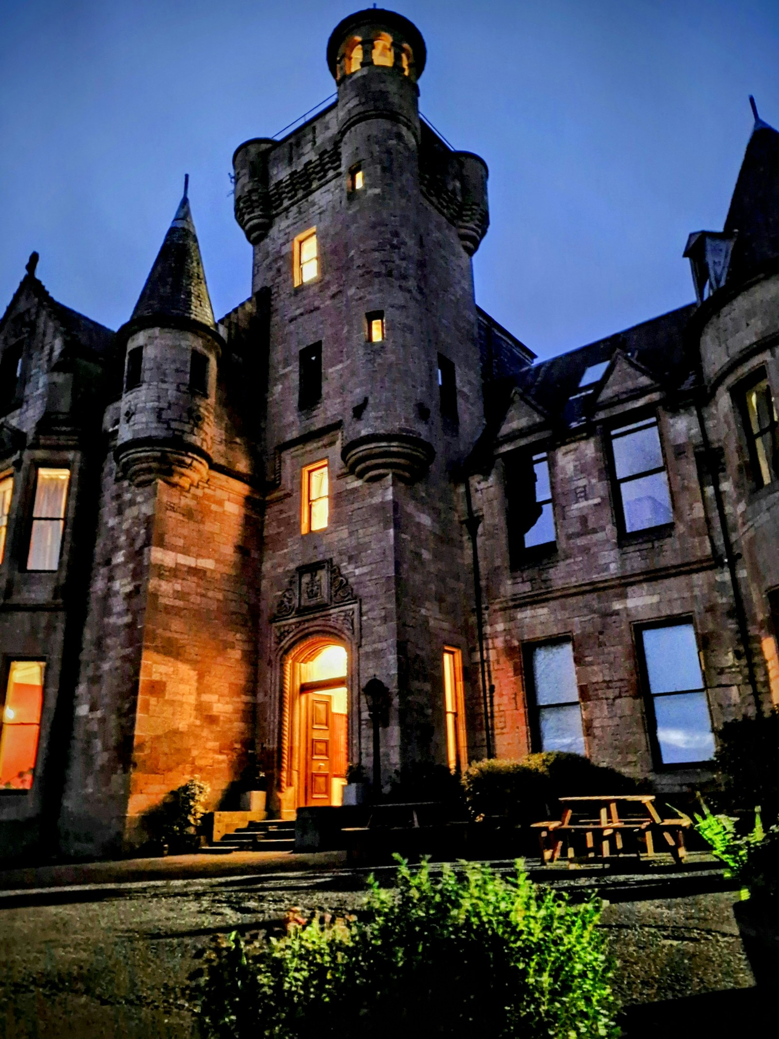 Broomhall Castle Hotel illuminated at dusk with lights glowing from the entrance and windows
