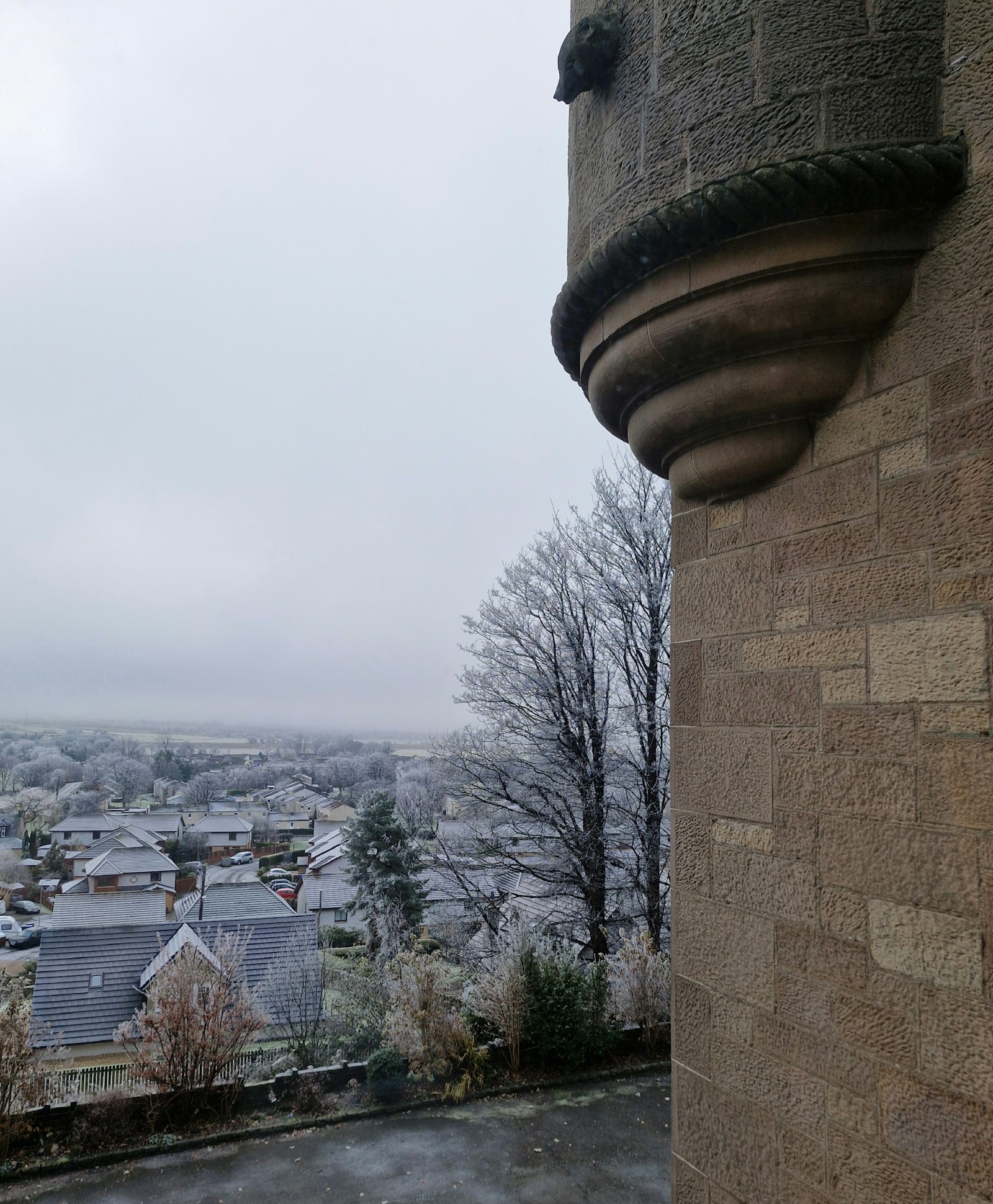Snow-covered Menstrie landscape viewed past a stone turret of Broomhall Castle