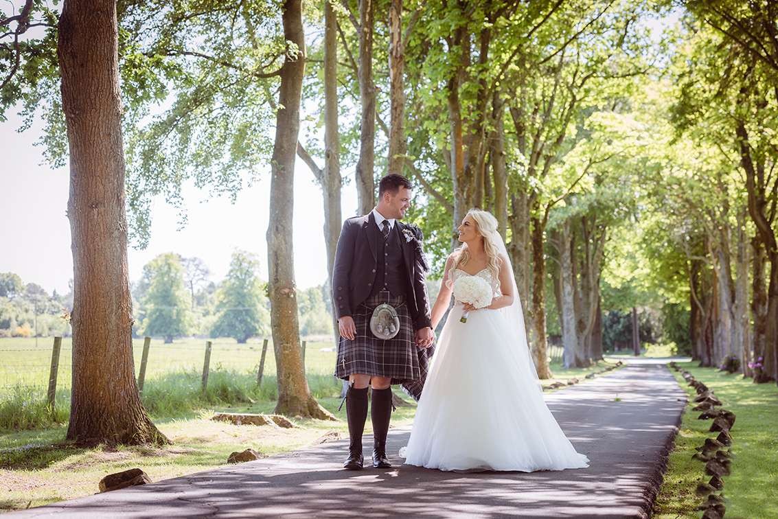 Bride and groom on Glenbervie’s tree-lined avenue.