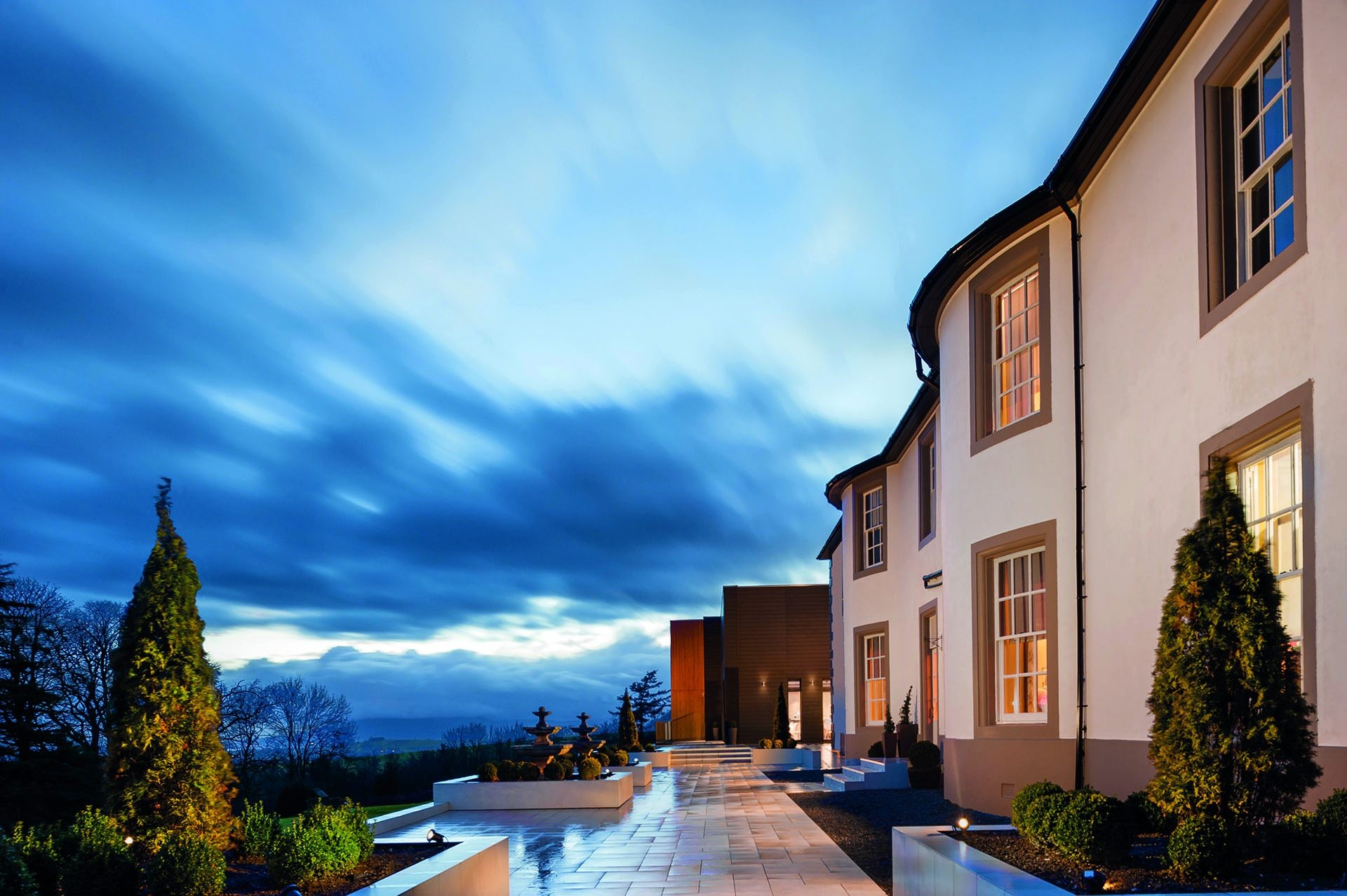 Hetland Hall Hotel exterior and fountain at dusk.