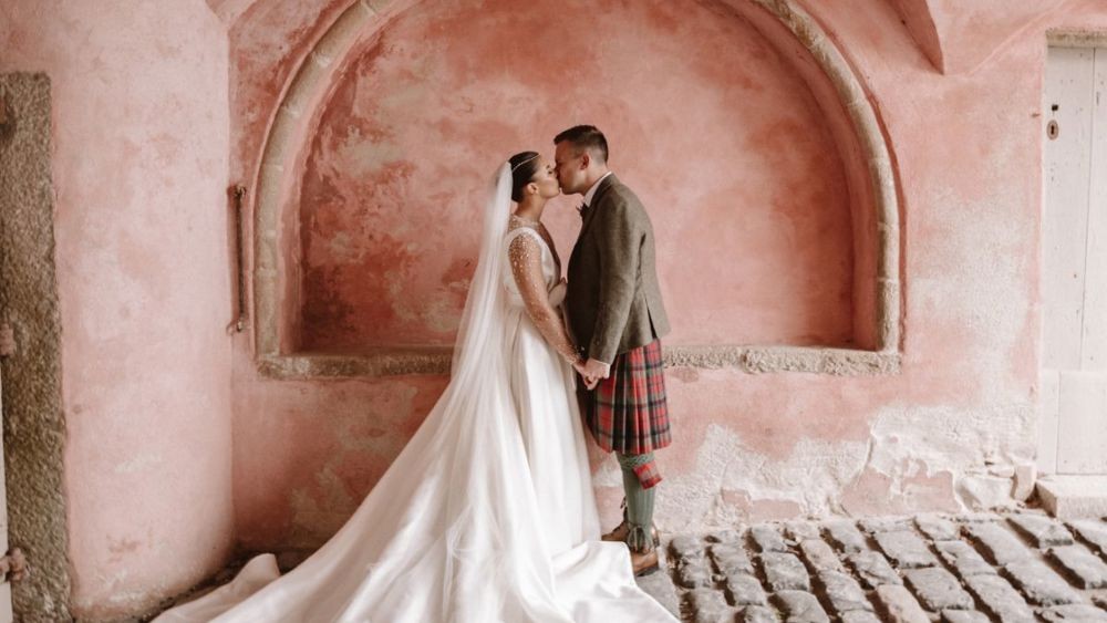 Newlyweds beneath a stone arch at Meldrum House.